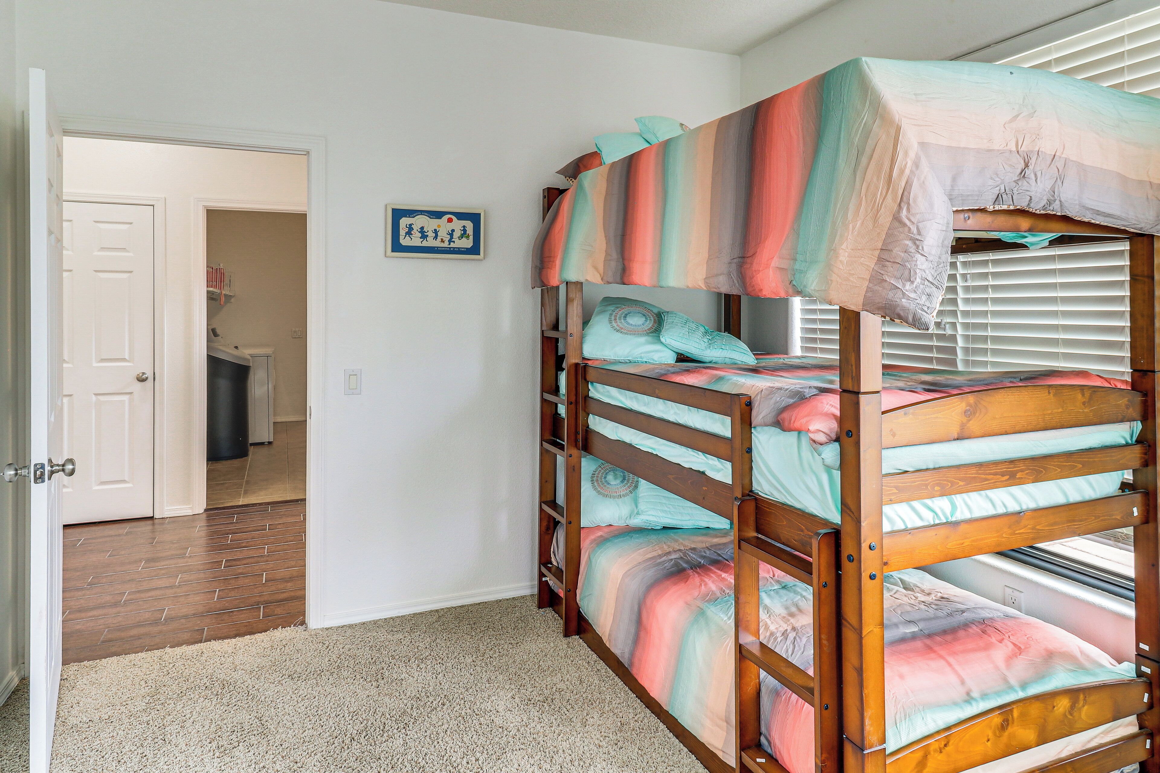 A bunk bed with a striped blanket, a door leading to a bathroom, and a small framed picture on the wall.