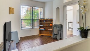 A living room with a flat-screen TV, a wooden bookshelf, and a potted orchid. - Furnished Rio Rancho Rental w/ Patio & Yard (Rio Rancho)