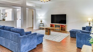 A modern living room with a large TV, blue sofas, a wooden coffee table, and a fireplace. - Furnished Rio Rancho Rental w/ Patio & Yard (Rio Rancho)