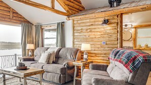 Et hyggeligt interiør i en træhytte med en sofa, lænestol og et lille bord med en lampe.