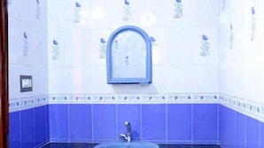 A bathroom with a blue sink, a mirror, and decorative tiles. - Fort beach Residency (Kochi)