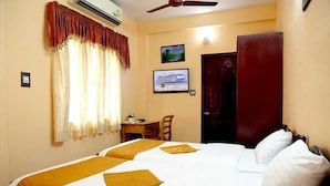 A hotel room with two beds, a desk, a chair, and a television on the wall. - Fort beach Residency (Kochi)