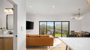 Cozinha moderna com uma ilha grande, área de jantar com vista e sala de estar com sofá e TV.
