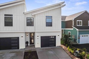 Une maison moderne à deux étages, dotée d’un garage, d’une porte d’entrée et d’un petit jardin.