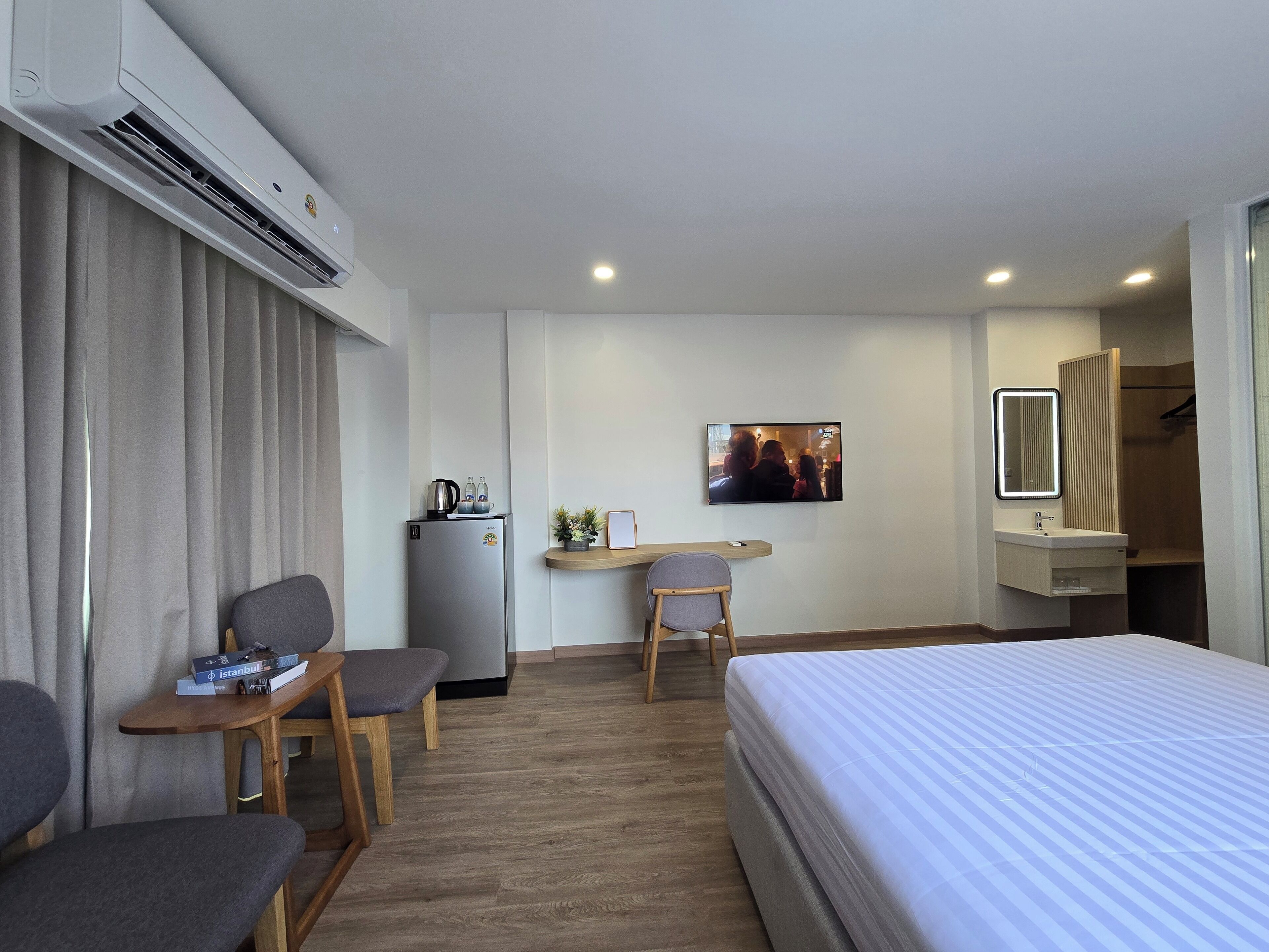 Une chambre d’hôtel équipée d’un lit, d’un bureau, d’une chaise, d’une petite table, d’une télévision et d’une salle de bain.