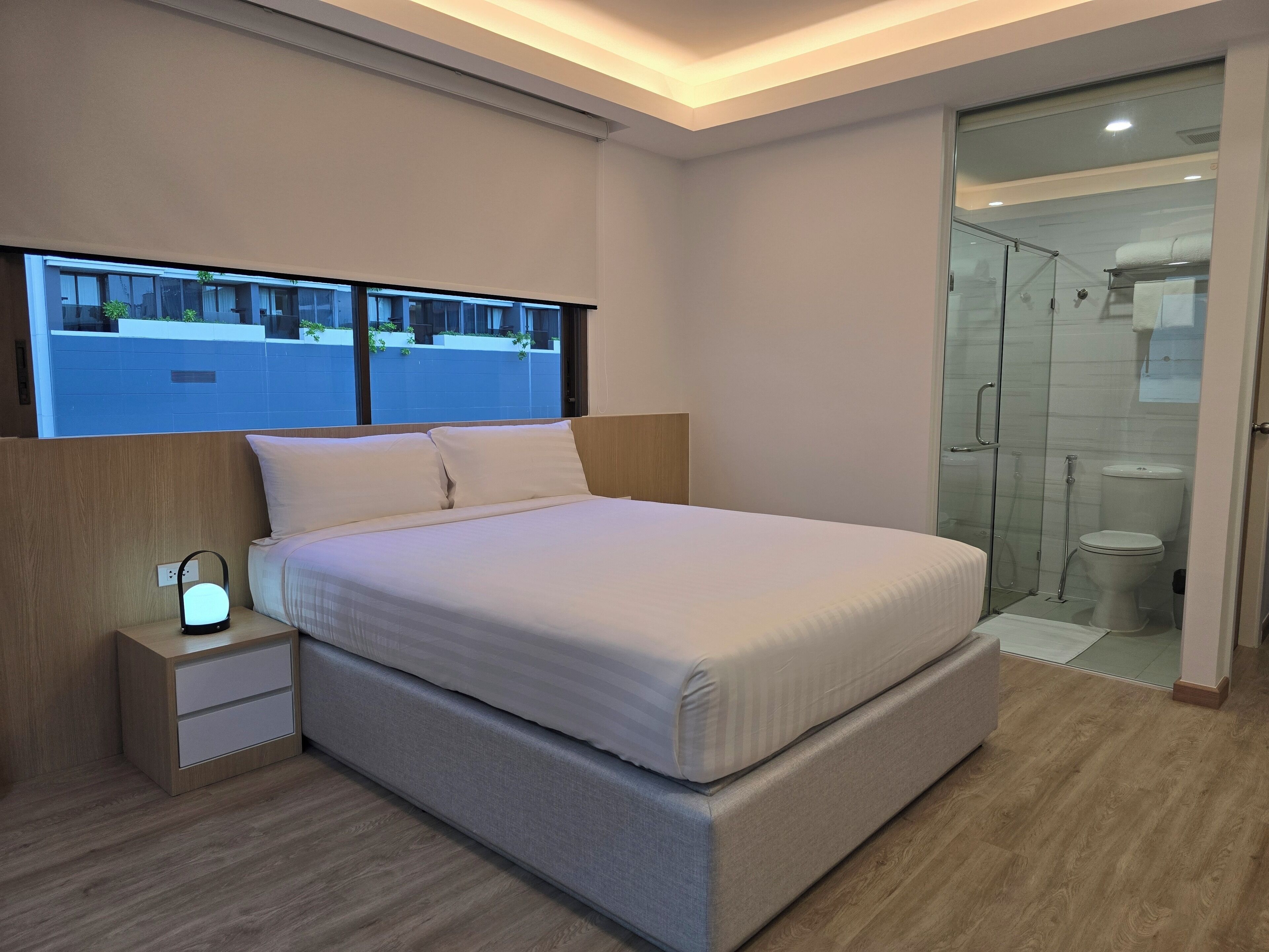 Una camera da letto moderna con un letto grande, un comodino e un tavolino con una lampada.
