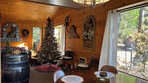 Ein gemütliches Blockhaus-Interieur mit Holzausstattung, einem Weihnachtsbaum, einem Esstisch mit Platzdeckchen und einem großen Fass.