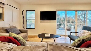 A modern living room with a sofa, a coffee table, and a TV mounted on the wall. - Unique Container Home · 20 Acres · Starry Nights · EV Charger (Placerville)