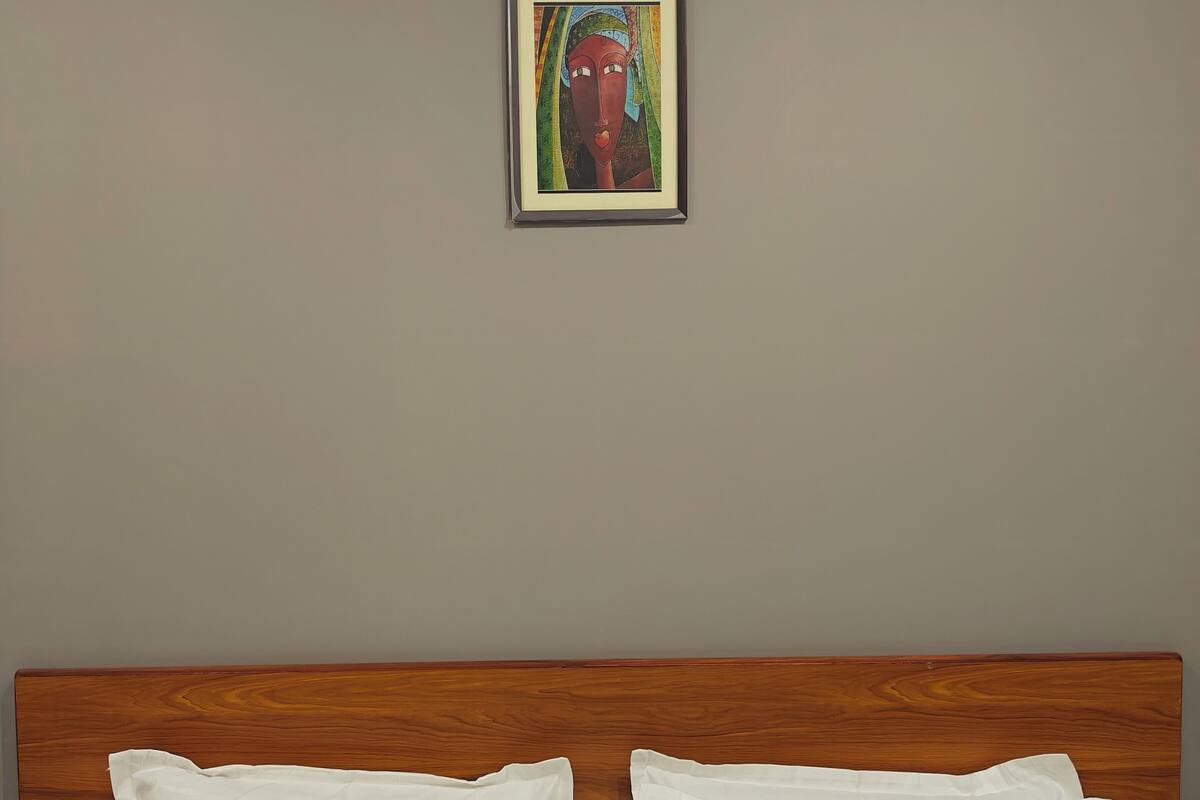 A neatly made bed with white linens and a wooden headboard.