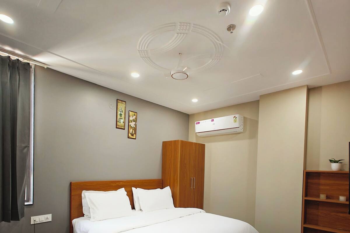 A hotel room with a wooden bed, a nightstand with a phone, a wardrobe, and a small wooden table.