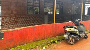 A red building with a metal roof and a scooter parked in front. - Coorg Heaven Home Stay (Madikeri)