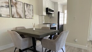 A modern dining area with a rectangular table, four chairs, and a pendant light.