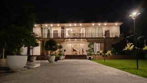A modern two-story building with a well-lit entrance and a covered staircase leading to the upper floor. - Garden Centre Resort (Kaliganj)