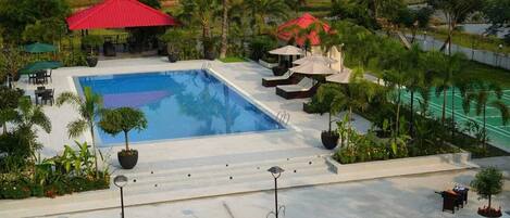 A swimming pool surrounded by lounge chairs, umbrellas, and potted plants.