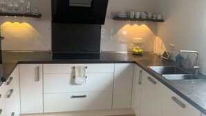 Eine moderne Küche mit weißen Schränken, einer schwarzen Arbeitsplatte und einem Edelstahl-Spülbecken.