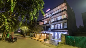 Un hôtel moderne à plusieurs étages, doté d’une entrée bien éclairée et d’une allée d’accès fermée par un portail.