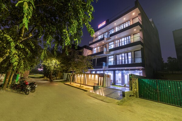 A modern hotel with multiple floors, a well-lit entrance, and a gated driveway. - Hotel Aura Grand SECTOR - 63A Noida (Noida)