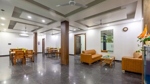 Un hall d’entrée spacieux, doté d’un plancher sombre poli, de meubles en bois et d’un ventilateur de plafond.