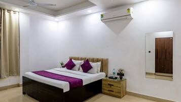 Un dormitorio moderno con cama, ventilador de techo, equipo de aire acondicionado, mesita de noche y un espejo en la pared.