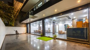 A spacious, modern interior with a polished floor, a motorcycle, and a green mat. - Hotel Aura Grand SECTOR - 63A Noida (Noida)