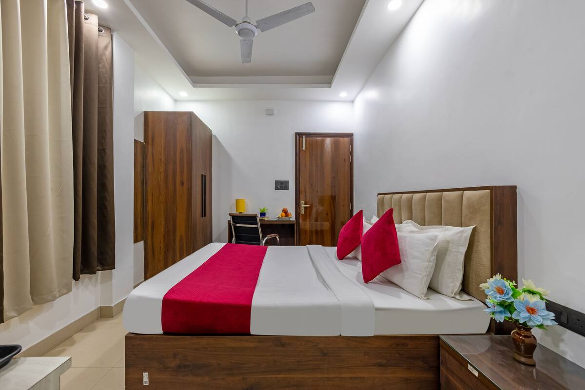 Une chambre d’hôtel moderne équipée d’un lit, d’une armoire en bois, d’un bureau et d’un ventilateur de plafond.