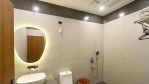 Un baño moderno con un espejo redondo, un lavamanos, un inodoro y una ducha.