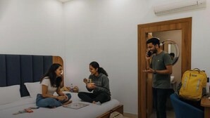 A room with a bed, a bedside table, a mirror, and a door. - The Metrostay Delhi (New Delhi)