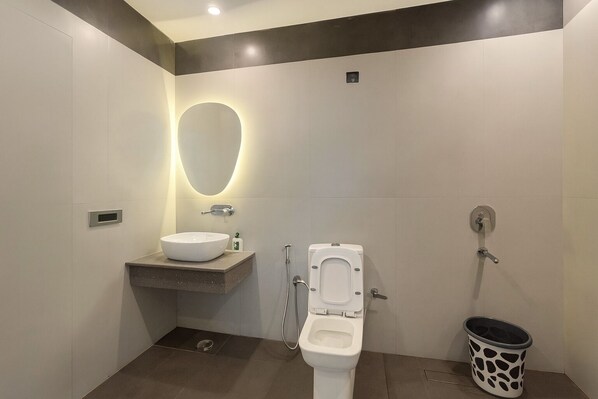 A modern bathroom with a white sink, a toilet, and a shower. - The Metrostay Delhi (New Delhi)