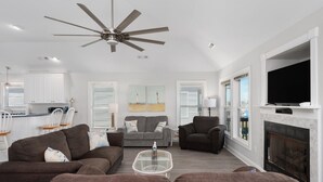 Un salon moderne doté d’un ventilateur de plafond, d’une cheminée et d’un téléviseur.