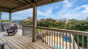 Une terrasse en bois avec une piscine et une vue sur les maisons au loin.