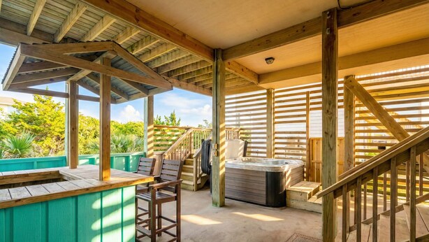Un espace extérieur abrité doté d’une terrasse en bois, d’un jacuzzi et d’un coin salon avec des chaises.