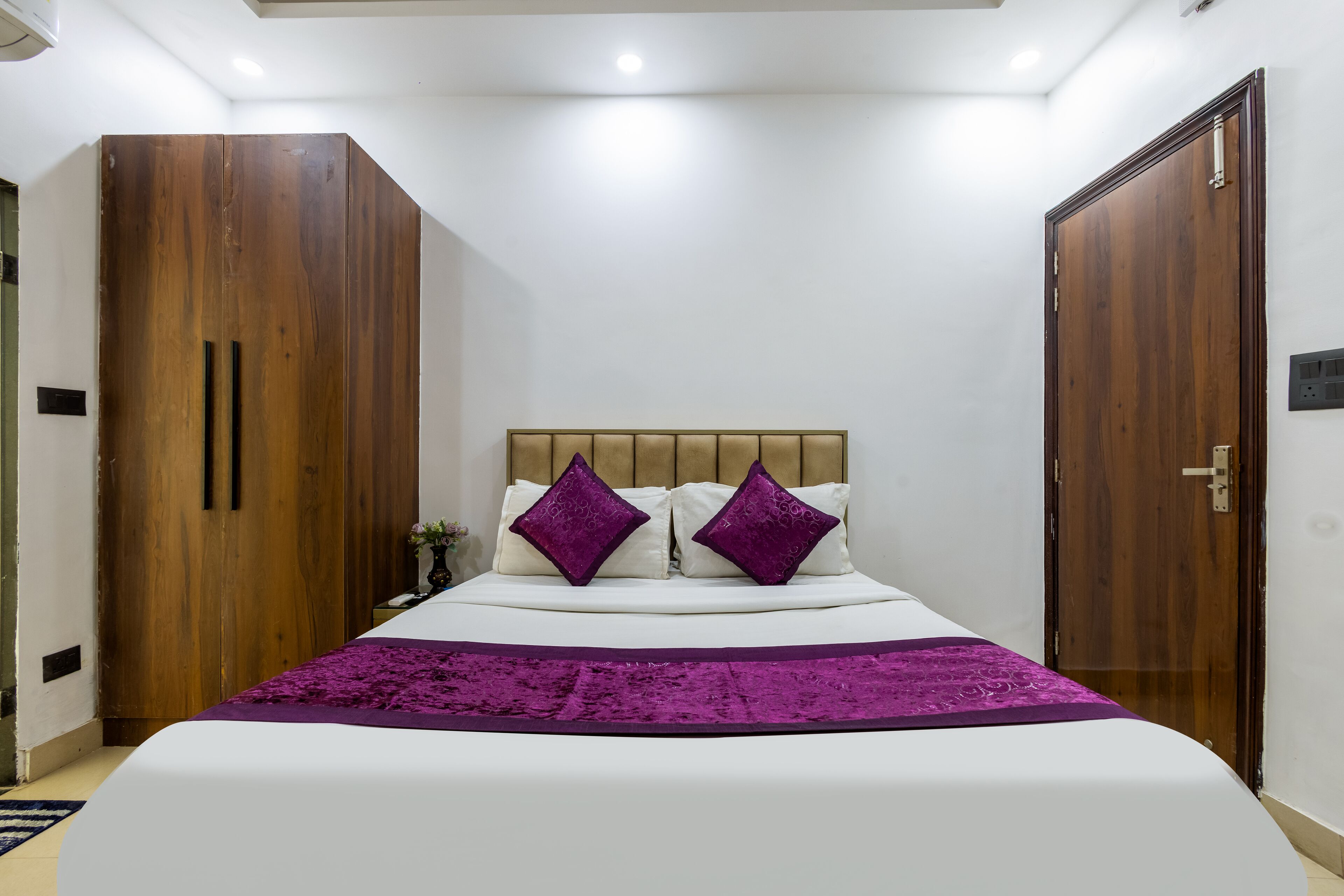 A bedroom with a large bed, wooden wardrobe, and a door.