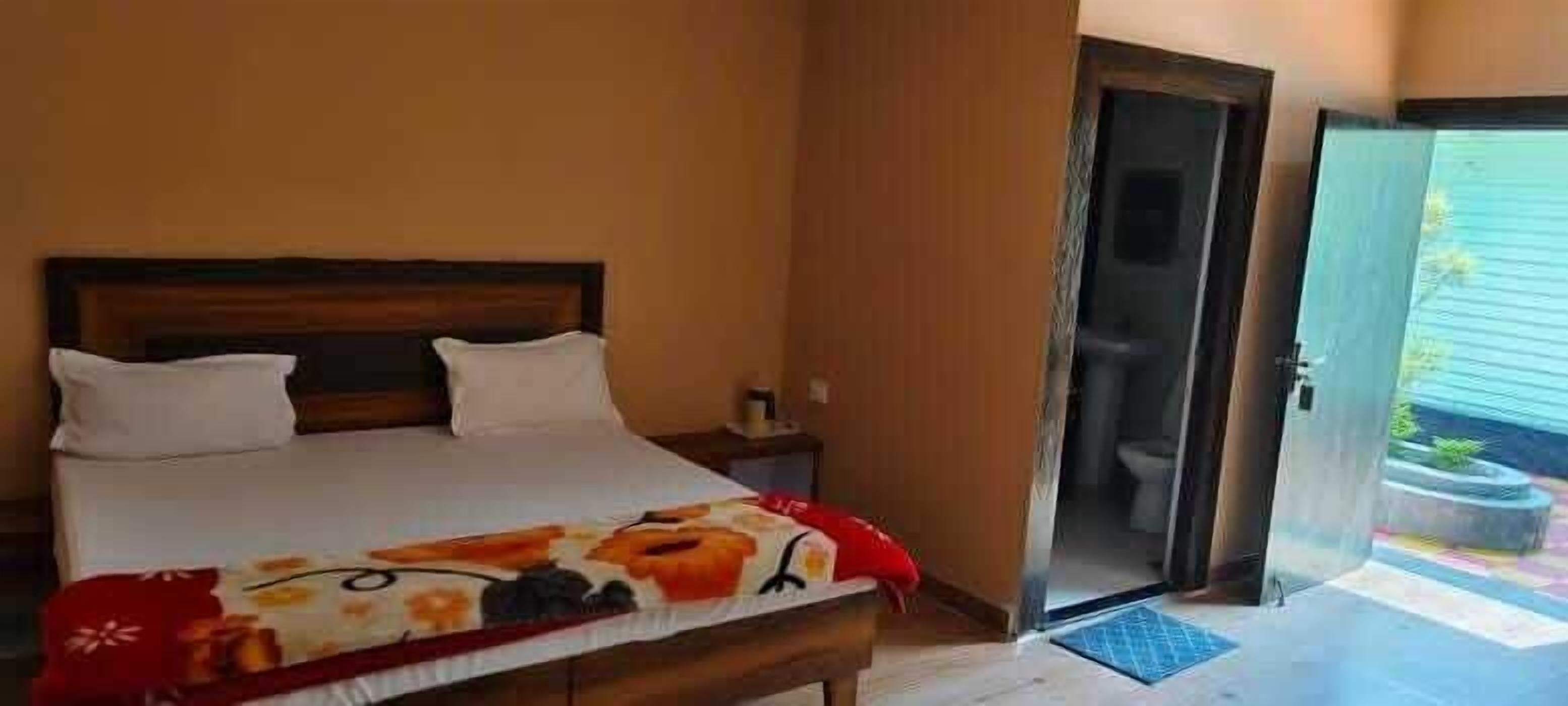 Une chambre à coucher avec un lit, une table de chevet et une porte ouverte donnant sur une salle de bain.