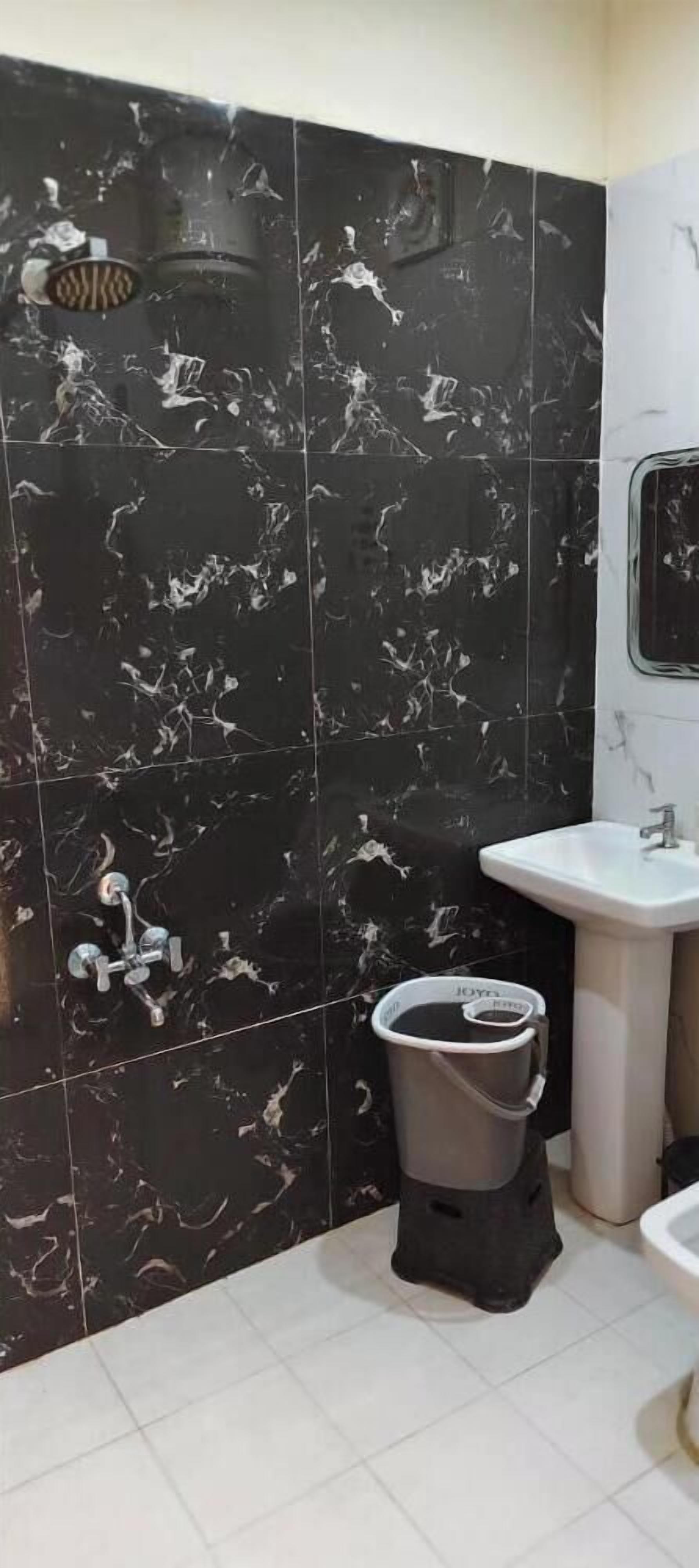 A bathroom with black marble tiles, a white sink, and a toilet.