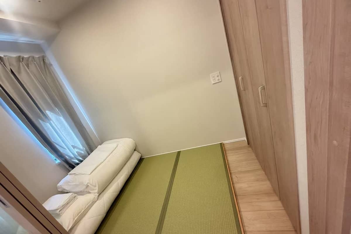 Una habitación pequeña con cama, un tapete verde y armarios de madera.