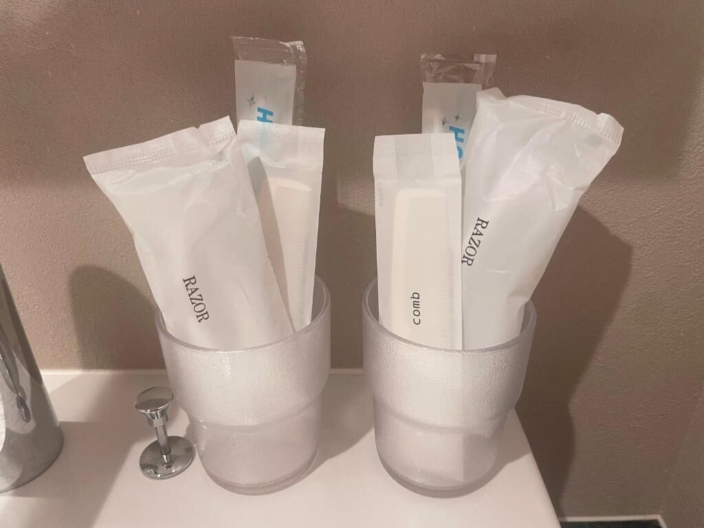 Due bicchieri di vetro trasparente con rasoi usa e getta bianchi recanti l'etichetta "Razor" e "pettine" su una superficie bianca.