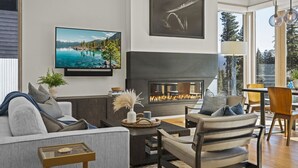 Una sala de estar moderna con chimenea, un televisor de pantalla plana y un comedor con sillas y una mesa.
