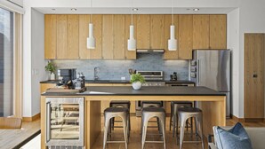 Una cocina moderna con armarios de madera, electrodomésticos de acero inoxidable y una isla central con taburetes de bar.