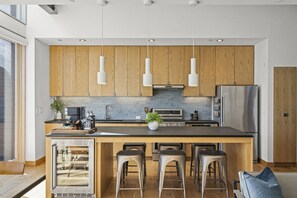 A modern kitchen with wooden cabinets, stainless steel appliances, and a central island with bar stools.