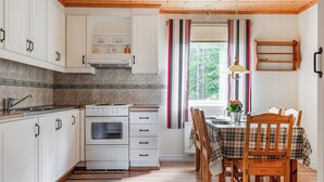 Una cocina con armarios blancos, una estufa y una zona de comedor con mesa y sillas.