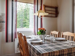A dining table with a plaid tablecloth, wooden chairs, and a vase with flowers.