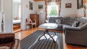 Una sala de estar acogedora con techo de madera, un sofá gris, un sofá de cuero marrón y una mesita.
