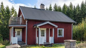 Una casa de madera roja con techo gris, puertas blancas y un pequeño porche.
