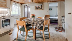 Une cuisine chaleureuse avec un plafond en bois, une table à manger avec des chaises et un tableau accroché au mur.