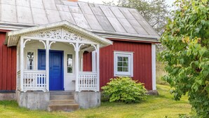 Une maison en bois rouge avec une porte bleue et un porche blanc.
