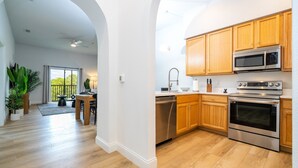 Una cocina moderna con armarios de madera, electrodomésticos de acero inoxidable y un comedor con mesa y sillas.