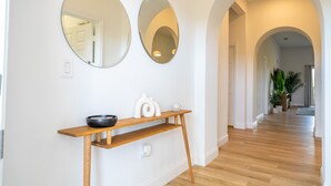 Un couloir doté d’un plancher en bois, d’une console sur laquelle est posé un bol, et de deux miroirs fixés au mur.