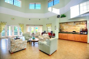 A spacious living area with multiple seating options, a large window, and a map of the Caribbean on the wall.