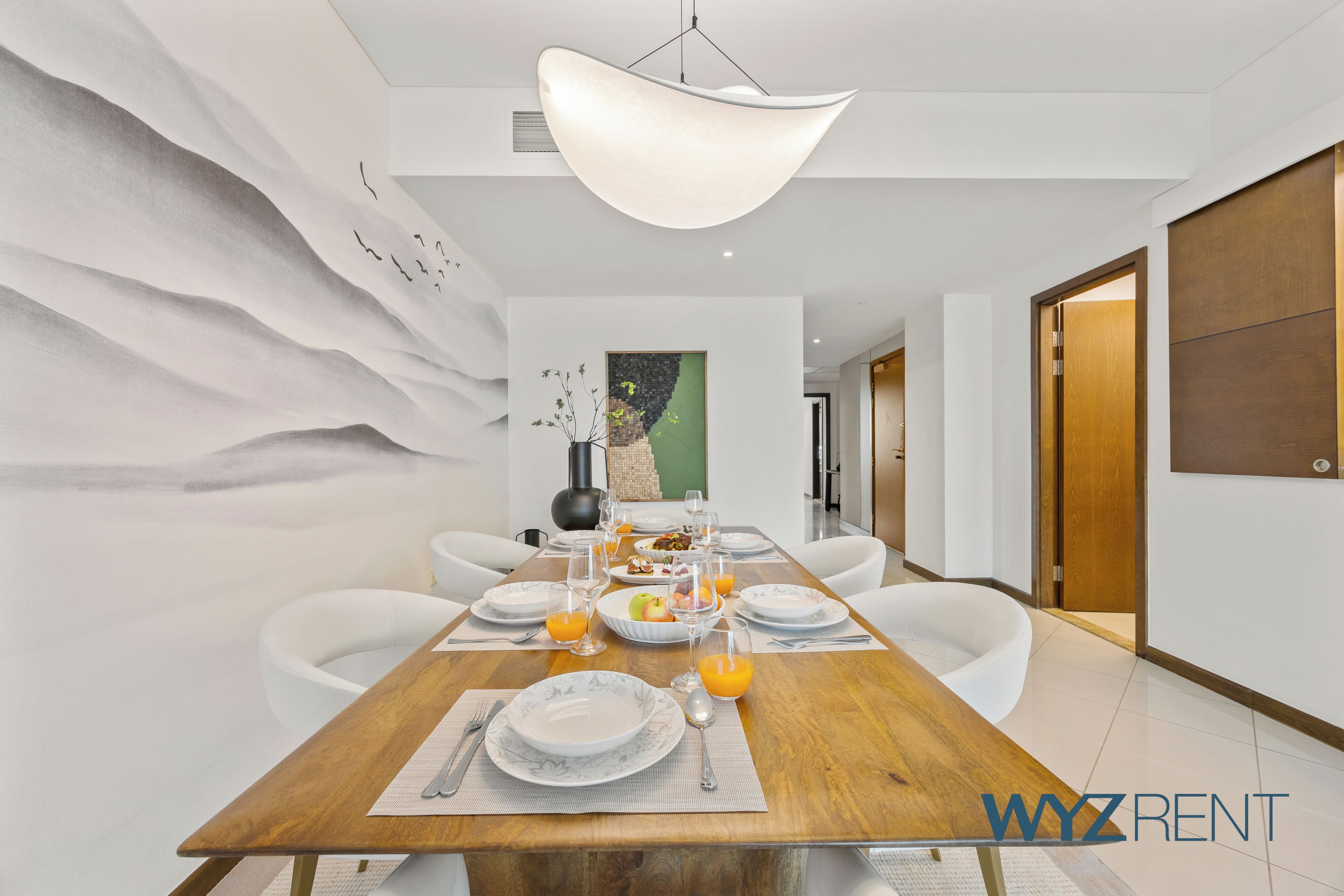 A modern dining room with a wooden table set for six, white chairs, and a large pendant light.