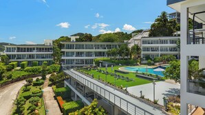 Ein modernes Hotel mit Dachpool, üppiger Bepflanzung und mehreren Gebäuden mit großen Fenstern.